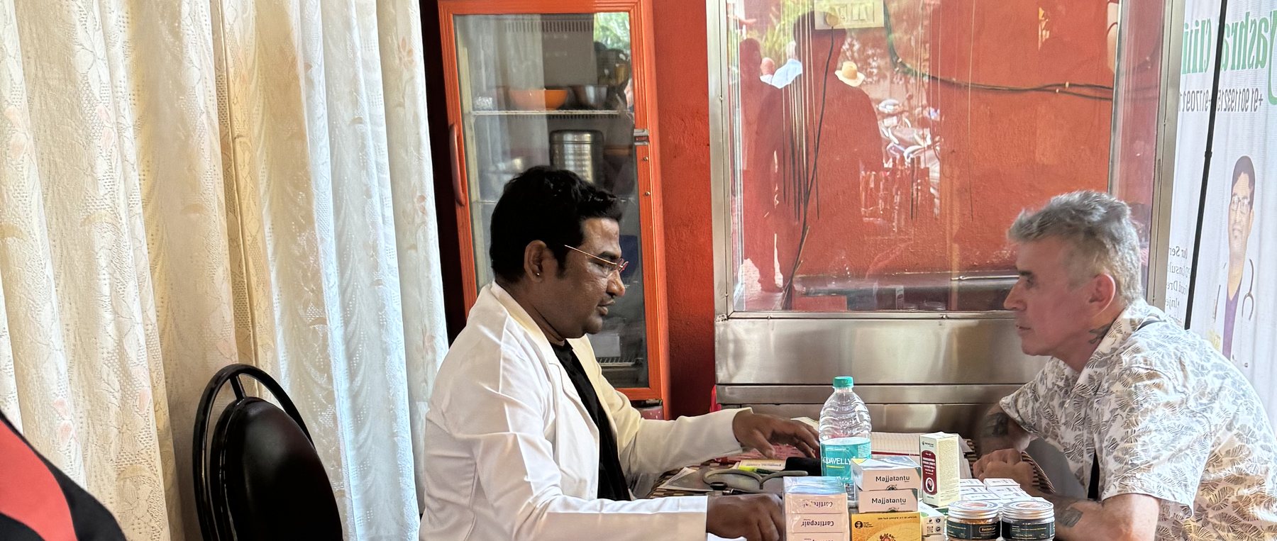 A treatment discussion at the clinic — the doctor walks the patient through the Ayurvedic medicines and the plan ahead